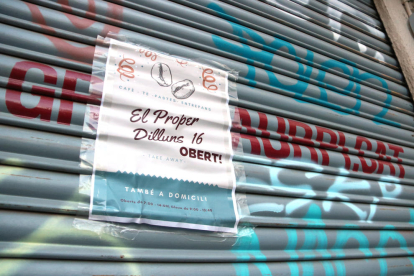 Un cartell en la persiana d'un local al centre de Sabadell anunciant la reobertura, el 22 de novembre de 2020