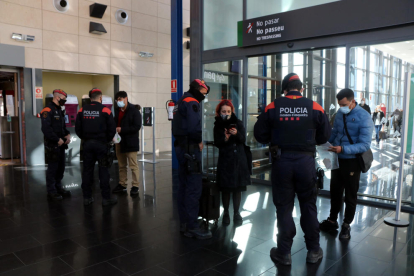 Varios viajeros del AVE mostrando certificados de desplazamiento a agentes de los Mossos d'Esquadra durante un control de movilidad.