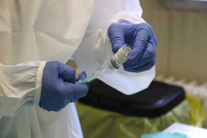 Una enfermera cargando una dosis de vacuna contra la covid-19 en una jeringa.