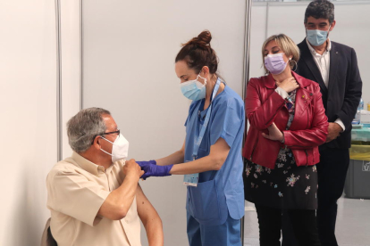 La consellera de Salut, Alba Vergés, mirant com administren una vacuna a un home al punt de vacunació massiva del Palau d'Esports Catalunya de Tarragona.