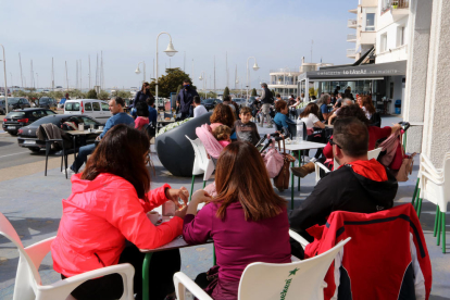 Personas consumiendo en una terraza de un bar de la zona marítima de l'Ampolla esta Semana Santa.