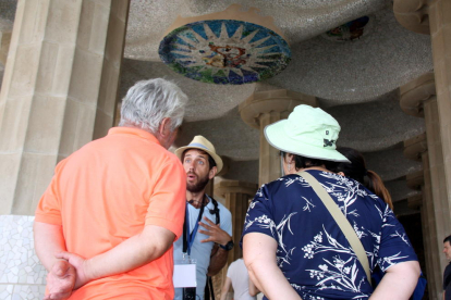 Un guía turístico dando explicaciones a un grupo de personas en la sala Hipóstila del Parc Güell.