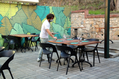 Pla general del copropietari del restaurant Botànic de Tortosa parant taules a la terrassa de l'establiment abans de la reobertura del migdia.