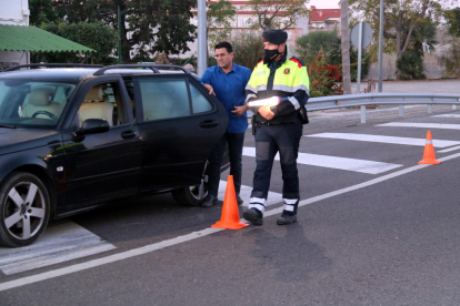 Plano general de un conductor mostrando la documentación y los certificados de movilidad a uno agentes de los Mossos en el control a la intersección de la N-340 en las Cases de Alcanar.