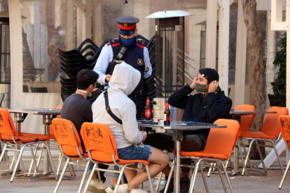 Un agent demanant a diversos clients d'un restaurant de la plaça de la Font que es posin la mascareta mentre no consumeixin