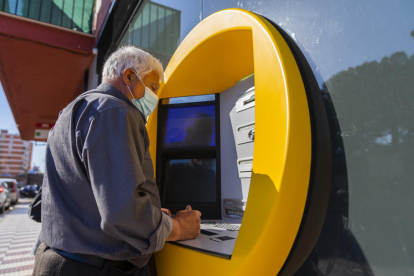 Una persona mayor del barrio de Sant Pere i Sant Pau haciendo gestiones a través de un cajero automático.