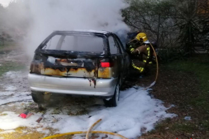 Un bomber treballant en l'incendi del turisme.