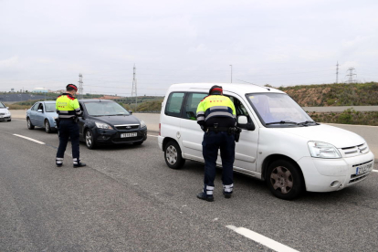 Dos agentes requiriendo la documentación a conductores parados en el control policial de la T-11 en Tarragona.