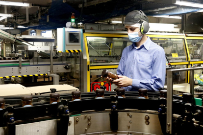 Un treballador inspecciona un pot de Nescafé al costat d'una de les línies de producció de la fàbrica de Girona.