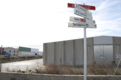 Senyals d'indicació al polígon industrial de Valls, amb unes naus en venda al fons.