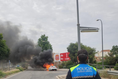 Un agent de la Guàrdia Urbana de Reus observant el vehicle cremant.