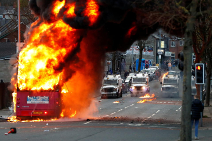 Vehicles policials darrere d'un autobús en flames a Shankill Road durant les protestes a Belfast.