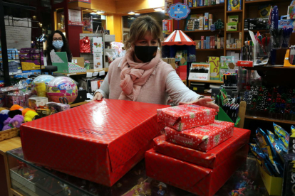 La presidenta presidenta de la Unió de Botiguers, Meritxell Barberà, entregant a una clienta regals embolicats, en el primer dissabte de la campanya de Nadal
