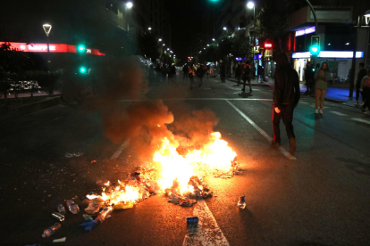 Basura quemando al suelo y un manifestante en la calle Prat de la Riba de Tarragona al inicio de los disturbios.