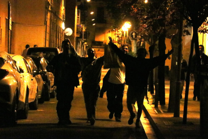 La silueta de varios jóvenes en la calle que celebran el final del toque de queda a Gracia