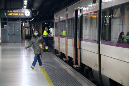 Plano abierto de una usuaria de Rodalies saliendo de un tren al andén de la estación de Sants de Barcelona.