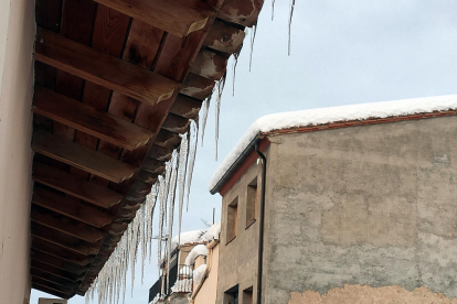 Primer plano de los candelabros de hielo colgado de un tejado en Arnes a primera hora de la mañana.