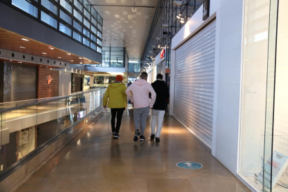 Un grupo de jóvenes caminando dentro del centro comercial L'Illa Diagonal con todas las tiendas cerradas.