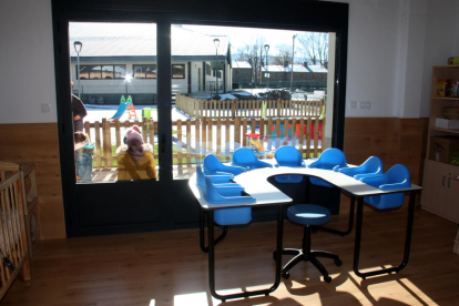 Un aula de un jardín de infancia y donde se ven alumnos del centro en el patio.
