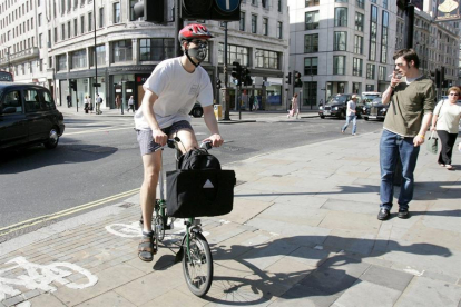 Un londinenc es dirigeix a treballar amb bicicleta amb mascareta a la cara a Londres.