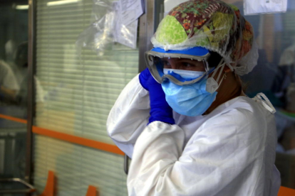 Una enfermera vestida con un EPI en una zona de UCI con pacientes ingresados a causa de la covid-19.