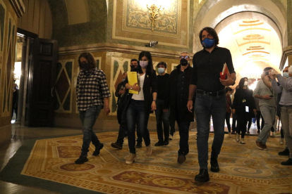 Plano general de los negociadores de ERC, Junts y la CUP caminando por los pasillos del Parlament después de la reunión a tres bandas.