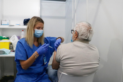 Una infermera vacuna un home en un dels box del punt de vacunació massiva habilitat a Fira de Barcelona.