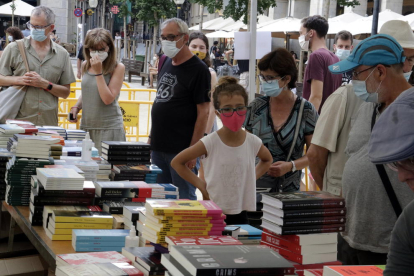 Compradors amb mascaretes mirant llibres al Sant Jordi d'estiu de Girona.