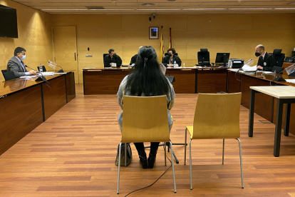 D'esquenes, la cuidadora acusada d'estafar una veïna de Girona. Foto del judici a l'Audiència de Girona.