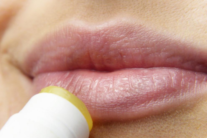Imagen de archivo de una mujer aplicándose un producto cosmético en los labios.