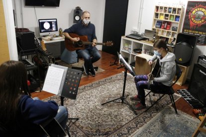 Albert Gilabert, profesor de guitarra del aula El Traster de Mollerussa, haciendo clase a dos alumnos, en la vuelta de las actividades extraescolares.