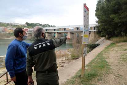 El jefe de los Agents Rurals en el Ebro, Miquel Àngel Garcia, y el biólogo del Grup Natura Freixe, Arnau Pou, señalando los márgenes de la presa de Flix.