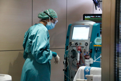 Una enfermera mirándose una máquina que ha filtrado la sangre de un paciente con covid-19 ingresado en la UCI de Vall d'Hebron.