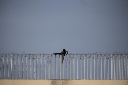 Un menor inmigrante no acompañado intenta saltar una valla, en Ceuta.