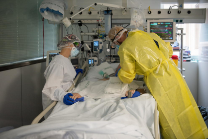 Dos sanitaris visitant un pacient de covid a l'UCI de l'Hospital Clínic protegits amb EPI.
