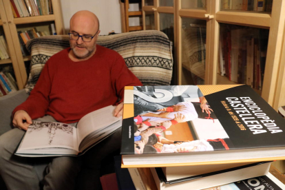 Xavier Brotons, responsable de la 'Enciclopedia castellera', sentado hojeando fotografías de la obra.