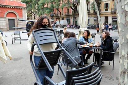 Treballadors del restaurant Amélie de la plaça de la Vila recollint taules i cadires amb gent encara menjant, e