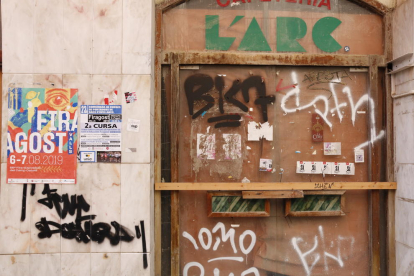 Grafits a la porta d'un antic establiment del carrer de la Cort, situat en un edifici històric conegut com Ca Padró.