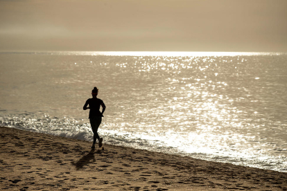 Imagen de archivo de una mujer corriente en la arena, delante del mar.