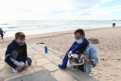 Jordi Llort, amb el seu fill Lluc, recollien plàstics ahir a la platja Llarga de Tarragona.