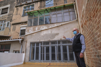 Pedraza, a la seva terrassa, mostrant l'edifici deshabitat que hi ha al costat de casa seva i d'on podrien sortir les rates.