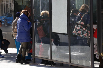 Imagen de archivo de gente protegiéndose del viento a una parada de autobús.