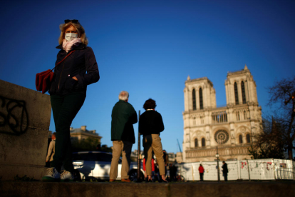 La gente con mascarillas ante la catedral de Notre-Dame de Paris durante la pandemia del coronavirus