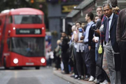 Trabajadores esperan en una parada de autobús de Londres.