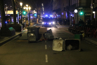 Una petita barricada amb contenidors a la Rambla de Barcelona, amb unes furgonetes dels Mossos en segon pla.