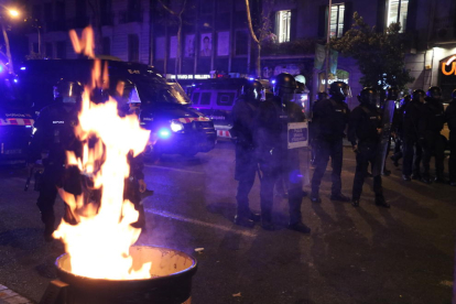 Agentes de los Mossos d'Esquadra junto a una papelera en llamas durante los disturbios posteriores a una manifestación de los CDR por el cuarto cumpleaños del 1-O.