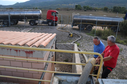 Uns operaris traspassant aigua dels camions cisterna al dipòsit de l'Espluga de Francolí.