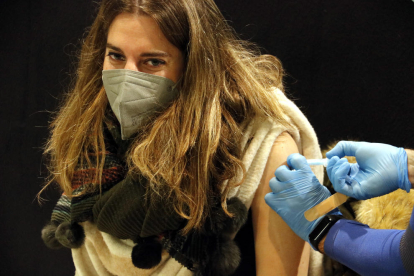 Imatge on es veu com posen una vacuna contra la covid-19 a una noia.