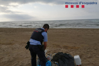 Un agente de los Mossos recogiendo la basura vertida en la Platjola de los Muntells.