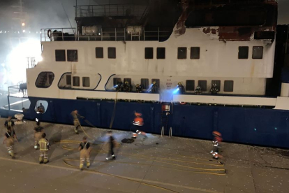 Imagen de esta pasada madrugada en el barco en el muelle de Levante y los bomberos inspeccionándolo.